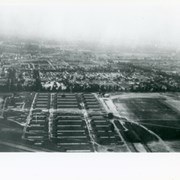 Looking east over barracks and main building at Ross Field.  Tree-lined street cutting across photo at far side of field is Santa Anita Avenue.  The oval of the race track built by E.J."Lucky" Baldwin and which opened in 1907 can clearly be seen on right.  Broad E/W street seen on far left is Huntington Drive.