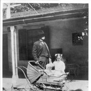 Elias J. "Lucky" Baldwin standing on porch of Hugo Reid Adobe holding hand of granddaughter Dextra Baldwin, who appears to be about 5 years old. Grandson Baldwin M. Baldwin is in wicker baby carriage and is about 1 1/2 or 2 years old.