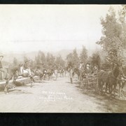 Elias J. "Lucky" Baldwin in carriage on his original track which was adjacent to Michillinda and near Colorado Blvd. With him is W. McClelland, Baldwin's horse trainer at this time. There are 16 other people in photo; some are mounted on horses, some standing. Etched on the photo is "On the track - Lucky Baldwins Place. S.G.V.R.R."