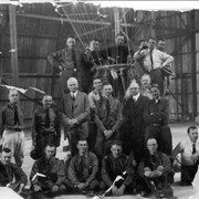 19 officers are in hangar at Ross Field in Arcadia as part of their training as Reserve Officers Balloon Personnel.  J.H. Hoeppel in white shirt is on the right (kneeling).  Lt.C.P. Kane, was in charge of the class.  He is 4th man from left (next to balloon) in second row.