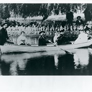 Rowing on the lake in a boat named CLARA are Clara Baldwin Stocker (second from right), Lucky Baldwin's elder daughter; Clara's fourth husband, Harold Stocker (rowing); and several friends.  A copy of this photo appears in the March 2, 1909 Los Angeles Daily Times pt.II p.8 with the following identification: FAMILY GROUP ON THE LAKE AT SANTA ANITA.  Left to right, in boat - Mr. Mathews, Mrs. F.D. Black, Mr. Stocker ("Lucky's son-in-law), Mrs. H.C. Wyatt, in white; Mrs. Stocker (Lucky's daughter) and Mrs. Scott.  There are seven people seated in the boat, but only six names are identified in the newspaper article. Article is in Arcadia History file Baldwin, Elias J. "Lucky", number 58 ("His greatest race run, 'Lucky' loses.)