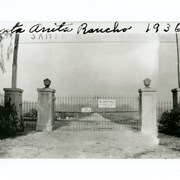 Iron gate and concrete posts of one entrance to Santa Anita Rancho with sign above showing only part of letters which read "Santa Anita Rancho."  Entrance was on Huntington Drive.