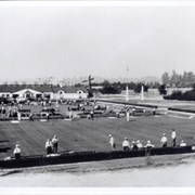 Lawn bowling at Arcadia County Park.  Men are wearing long sleeve white shirts, ties and hats.  Race track is visible in distance.