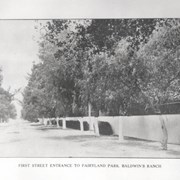 Photo from a page of the 1907 Los Angeles Racing Association Souvenir Booklet  showing, "First Street Entrance to Fairyland Park, Baldwin's Ranch." First Street runs along the left side of the photo, with the outer wall of Fairyland Park along the right, lined with trees.  Photo #923 is an enlarged view of this photo.