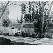Photo of a painting by John Henry Lewis of two girls picking flowers by the lake with portion of Queen Anne Cottage and Hugo Reid Adobe shown.  Painted in 1885.