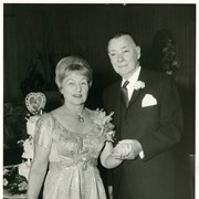 Photo of Charles and Billie Eaton, taken at what might have been a 50th wedding anniversary celebration.  They are both in formal attire.  A 3-tier cake is visible just over Mrs. Eaton's shoulder.