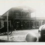 Exterior of the main building of the Pony Express Museum.  The photo is taken through a barbed wire fence and is washed out along the upper right corner. The front left part of a car is visible in the right corner.