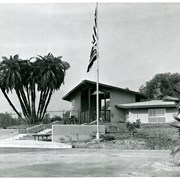 Administration Building at the Arboretum.  A flag pole with two flags is in the center of the photo. No one is visible.