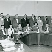 City Council members standing behind unidentified seated youth in what appears to be a "Student Government" day.  Council name plates read: Conrad T. Reibold, Elton D. Phillips, Robert F. Dennis and Donald Camphouse.  Not all name plates are visible.  Photo appears to have been taken in Council chambers.