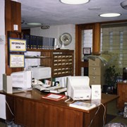 Photo taken of Arcadia Public Library, 20 W. Duarte Road, during the 1995/96 expansion/remodel project.  This view is of the temporary reference desk, located near the fireplace in the south end of the library.  A sign identifying the desk as an "Information Desk" is visible to the left.