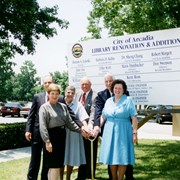 Groundbreaking ceremonies for the remodel/expansion project at Arcadia Public Library, 20 W. Duarte Road.  This photo shows six people standing in front of a large sign announcing the renovation and listing the names of council members, Library Foundation members and others.  Standing L-R holding onto a shovel: Kent Ross, Joan Scott, Mavis Dumbacher, Don Swenson, Jesse Vanlandingham, June Fee.