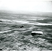 View east shows two balloons aloft over Arcadia and San Gabriel Valley. It is possible that first river up from bottom of photo is Rio Hondo Wash.  Some of trees along Santa Anita appear to be in extreme lower right of photo. Tree-lined street showing in extreme lower left of photo is Duarte Road. Second river coming into photo about five inches up from bottom of photo would be San Gabriel River.