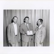 Three men in suits, posing with a National Safety Council Award for the Arcadia Police Department. Date on award reads 1955-1956. Men in the middle is Eric Topel. See also photo ID 1769.