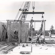 Construction in progress of the one-story Arcadia Police Department building at 250 W. Huntington Drive. Crane, pulleys and at least six workers are shown.