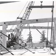 Construction in progress of the one-story Arcadia Police Department building at 250 W. Huntington Drive. Crane, pulley, and workers put up frame of the building.