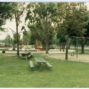 Eisenhower Park, showing swings, children's playground, and wooden picnic tables.