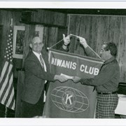 Arcadia Recreation Department employee Jerry Collins holding up a Kiwanis Club flag, handing something off to a Kiwanis member. Copies 2 and 3 are slightly different versions of this photo.