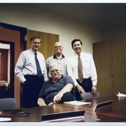 Arcadia Recreation Department employee Jerry Collins is standing in the middle, in a conference room, with three other men, identified on the back as Pauly, Gibson, and Phillips (in no particular order).