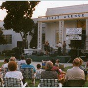 Arcadia Recreation Department summer concert at First Avenue School front lawn. A band plays on a stage for people who have brought their own lawn chairs. Although the back of this photograph is stamped with its processing date of August 1997, "Summer Concert 1996" was handwritten on the envelope it came in from Arcadia Recreation Department.