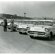 Captain Jim Hayes taking delivery of a new fleet of 1957 Chevrolet police cars. Santa Anita Park's grandstand is in the background.