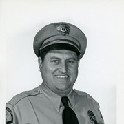 Portrait of Arcadia Police Officer Jim Hayes, in uniform (hat, badge, necktie, patch).