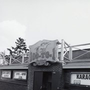 Exterior view of 100-to-1 cocktail bar at 100 W. Huntington Drive. This horse racing themed bar was demolished 2015. Signs read "Complimentary buffet" and "Karaoke." Murals inside were salvaged by Gilb Museum. Photograph by Terry Miller.