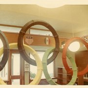 Children's Room, Arcadia Public Library, 20 W. Duarte Rd. decorated for Summer Reading Club with 1968 Summer Olympics theme, featuring Olympic rings, flags and emblems of various nations. Shows interior furnishings and details such as globe pendant lights, and shelving