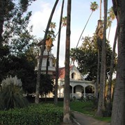 Queen Anne Cottage with red trim at the Los Angeles County Arboretum. Palm trees and stone-lined path. Arboretum address is 301 North Baldwin Avenue, Arcadia, CA. Any use of this image must be credited "Photograph by David Stevens. Copyright David Stevens."