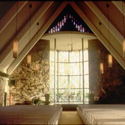 Interior of Santa Anita Church, address 226 West Colorado Boulevard. It has an A-frame roof, as also seen from the aerial photos by David Stevens. Pendant lights. Glass enclosed altar, stained glass, stone work walls, and light-colored pews. Any use of this image must be credited "Photograph by David Stevens. Copyright David Stevens."