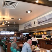 Interior view of Rod's Grill showing customers eating at counter and at tables in booths. Also pictured are some waitresses and cooks, as well as two of the historic photos that the restaurant displayed on its walls. Rod's was located at 41 W. Huntington Drive in Arcadia, along Historic Route 66, from 1957 through February 2023.