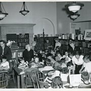 Children's Room at Arcadia Public Library at 25 N. First Avenue.  Standing left to right:  Judith Moore, Mary Lou Fitts, Hazel Boulton, Mary Lou Harbin, Geneva Jones, teacher.  In foreground, in white blouse, is Louise DuMond, City Librarian.