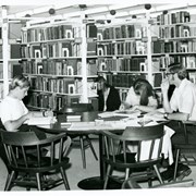 Patrons studying at Arcadia Public Library, 20 W. Duarte Road.  Two boys and one girl at a table, one additional girl is in the stacks selecting a book.