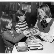 Children's Librarian Eva Swedstedt, shown giving books to young girl while boy watches.  Eva Swedstedt was Children's Librarian from about 1972-1977. Arcadia Public Library, 20 W. Duarte Road.