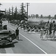 What appears to be an American Legion Girl's Drum & Bugle Corps marching on Huntington Drive near Santa Anita Race Track parking lot during Peach Blossom Festival.