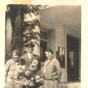 Three people standing behind small table that has large bouquet of roses on it.  Left to right: ?, Mayor A.N. Multer (1926-1930), and Gladys Randall, City Clerk. We believe this identification is correct, but lady on left could be Gladys Randall.  May have been taken outside one entrance to City Hall at corner of First Avenue and Huntington Drive.