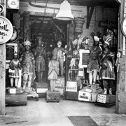 Collection of eight store-front figures grouped around door into Pony Express Museum.  Also shown on left: large watch advertising Ingersoll watches and on right one advertising Sherrar clocks.