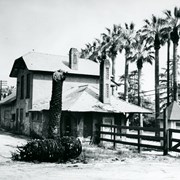 View from west end of Santa Anita Santa Fe Station when it was abandoned and in great disrepair. There is a large piece of palm tree trunk lying on ground near a fence.