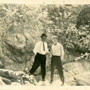 Leo Bertolina on left amd Jim Newton standing beside Stone Canyon wall. Back of card places location as just north of Foothill near First Avenue.