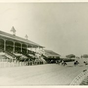 Grandstand and portion of track at Ascot Park, a racetrack built near the center of Los Angeles that offered racing from 1903-1907.  It was closed due to a city ordinance forbidding gambling.  Baldwin's track, Santa Anita Park, which opened in December 1907 was designed and built by the same architect that built Ascot Park: A.M. Allen.  The two tracks are similar in style and are occasionally mistaken for each other.  In this photo the stands are full and there are eight horses with jockeys on the track.