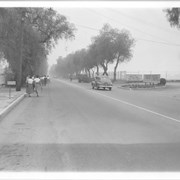 View west on Duarte Road from near intersection with Santa Anita.  Street is lined on both sides with pepper trees.  Note mailbox on left bears the number 20 W. Duarte Road - the current address of Arcadia Public Library.  Groups of students are walking on south side of street to newly opened Arcadia High School which is on the right.