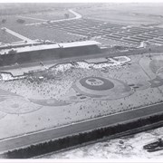 Aerial view toward SW from position just north of Santa Anita Race Track with large crowd in attendance.  View shows planting design on the infield, the clubhouse, and to the west, the former training track belonging to Santa Anita.  This and stables were removed or relocated to make room for the Fashion Park.  Baldwin Avenue was not cut through at this time. This photo belongs to the Huntington Library. It is shown here for research only.