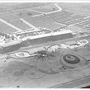 Aerial view looking south over Santa Anita Race Track on a day of very heavy attendance.  The floral plantings which form designs in the in-field are shown clearly.  Also seen are: the clubhouse, the stables, and the training track. These latter were either moved or done away with to make way for the Fashion Park.  Main gate was at NE corner of Huntington Drive and Baldwin, which was not cut through at that time. This photo belongs to the Huntington Library. It is shown here for research only.