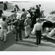Arriving automobiles and their occupants' luggage are checked.  In this photo, seven Japanese men watch and wait during the check, also two women. Four authorities do the checking at Santa Anita Assembly Center for the Japanese.