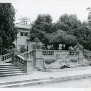 View toward entry to Anoakia taken from drive.  Double stairs rise to level lawn.  Front door can be seen about in center of building.  Bas relief sculptured fountain is seen between stairs.