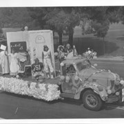 Truck float bearing the name of Jr. Exchange and Pep Commission. Eight young people are shown on the float.  Photo taken along Campus Drive by County Golf Course during Diamond Jubilee Parade.