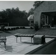 View of covered recreational area of home of Dr. Alva Surber in the Oaks area.  A tennis court can be seen, as sell as the deck area around a swimming pool with 2 canvas chairs.  This house was at 1014 Hampton Road.