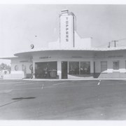 View across parking lot toward Topper's Drive-In, which opened in December of 1941.  It was located on NW corner of Baldwin and Huntington Drive and was owned by C.A. Price (according to info in Rancho Santa Anita Scrapbook #5, p.45).  Around sides of building are signs reading: Sandwiches, Fountain dinners and Dining Room.