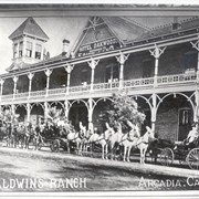 One carriage and two tally hos are stopped in front of Oakwood Hotel.  About 18 people are seated in the conveyances.  White horses hitched to middle tally ho, have white plumes fixed to their harness.  Sign above reads: Hotel Oakwood - Entrance to Fairyland.  On the bottom of photo is printed: Baldwin's Ranch, Arcadia, Cal.
