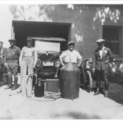 Photo showing what appears to be part of an illegal still.  Five men are shown.  Med Cayer, Arcadia police officer, is 2nd from left.  Arcadia police officer Jack Miller is on extreme right.  The men are standing in front of a building with a car behind them.  There are two motorcycles visible on either side of the group.  Med Cayer and Jack Miller are in uniform, the other three men do not appear to be in uniform. Identification provided by Arcadia Police Sgt. Andrew Ballantyne.