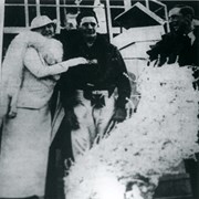 Anita Baldwin congratulating jockey Richards and trainer Handlen probably in 1935 or 1936.  Floral piece appears to be in the shape of a peacock. Note the Maltese cross on front of jockey's trousers.